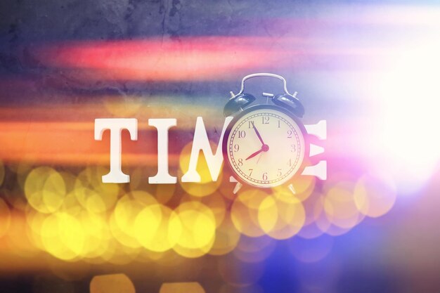 Photo background with a clock on the table and bokeh in pastel rainbow colors time for rest and travel