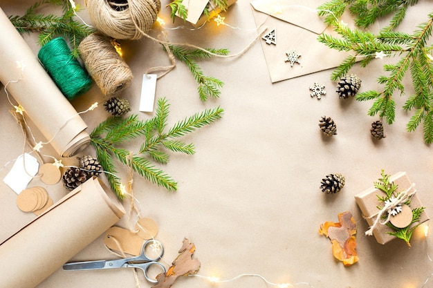 Background with copyspace for Christmas and new year in eco-friendly materials: kraft paper, gift box, live fir branches, cones, twine. Tags with mock up, natural decor, hand made, DIY. Flatly