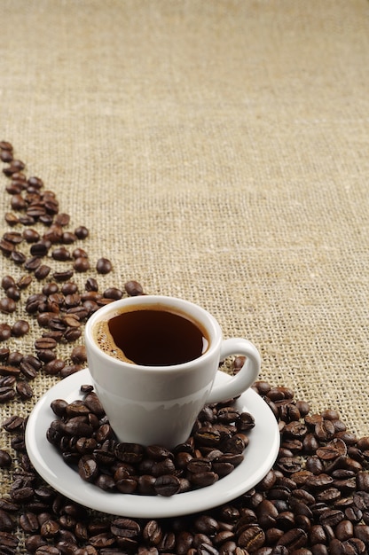 Background with cup of coffee and coffee beans on round fabric