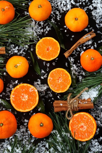 Background with cut and whole tangerines on a dark table with snow top view