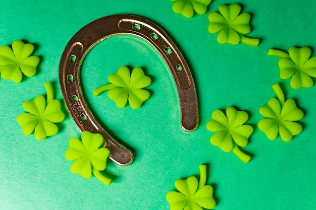 background with gold horseshoe and plastic clover leaves on green table
