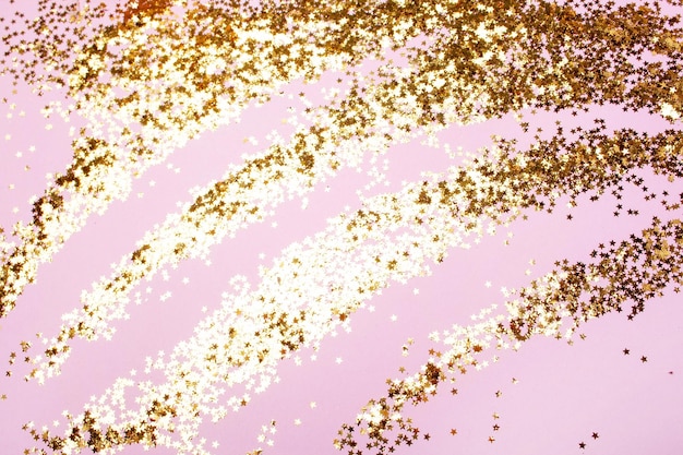 Background with gold sequins stars on a pink background Festive decor View from above