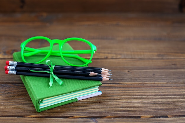 Photo background with pencils and glasses and a book.