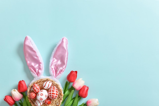 Background with rabbit ears tulips and Easter eggs on a blue background