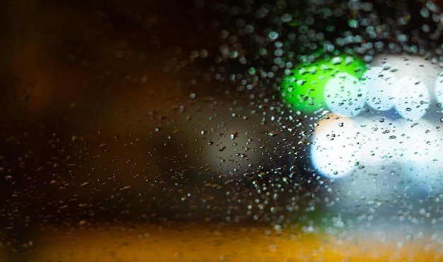 Background with raindrops on window and street lighting colors