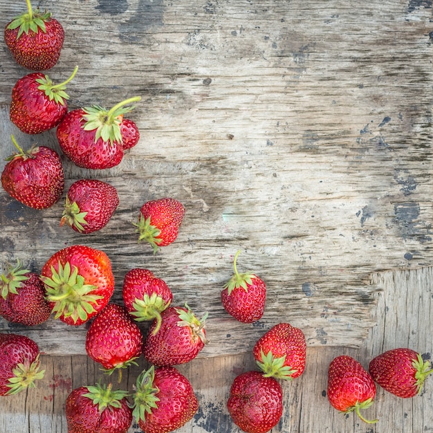Background with strawberry on a textured wooden surface with cop