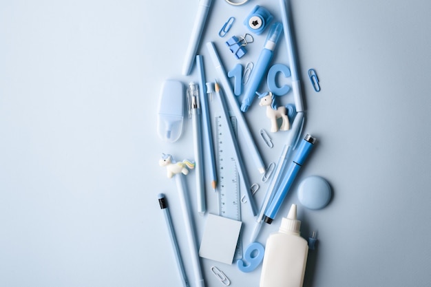 Background with various light blue stationery lying in the center Back to school