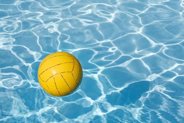 Background with yellow ball in the swimming pool and copy space