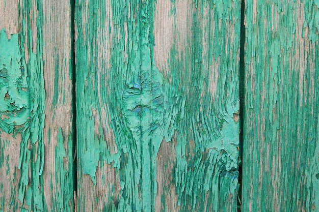 The background of wooden boards painted green peeling paint.