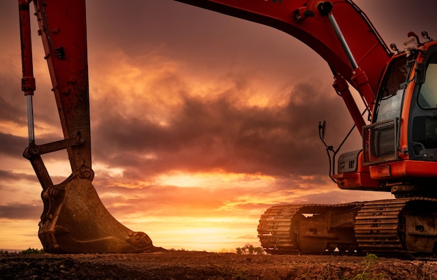 Photo backhoe parked at construction site after digging soil bulldozer on sunset sky and clouds