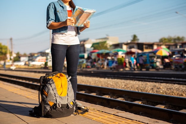 Photo backpack and asian woman holding map at the train station with a traveler. travel concept.