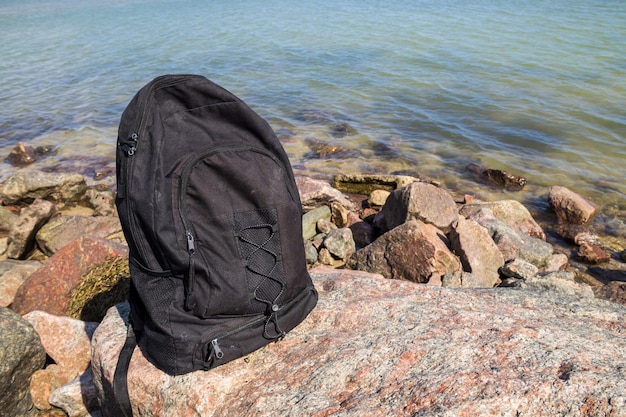 Backpack on rock with sea shore background