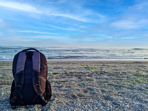 a backpack in the sand on the beach with copy space