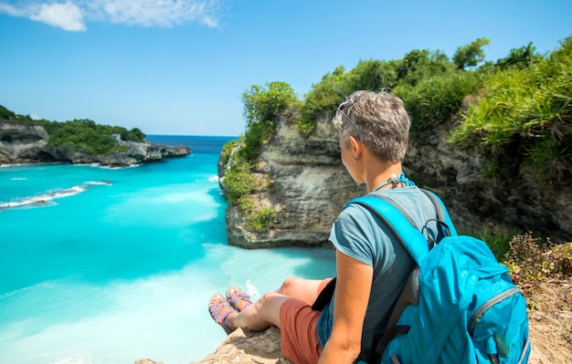 Backpack traveler sitting near sea cliff