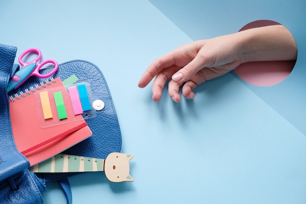 Backpack with different colorful stationery on table.