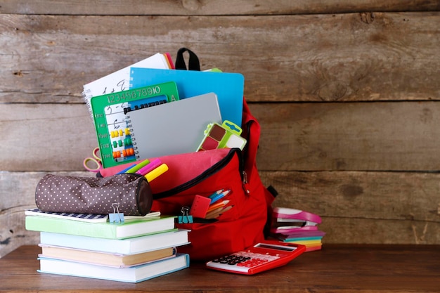 Backpack with school supplies on old wooden table