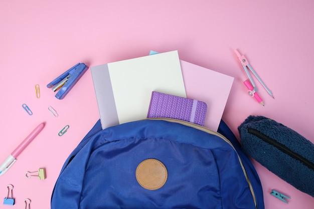 Backpack with school supplies on pink background Back to school concept
