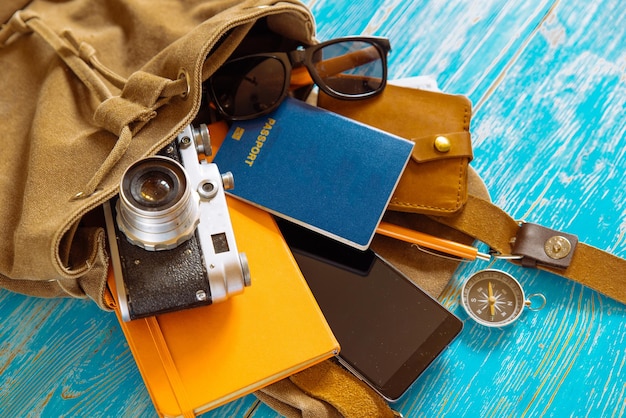 Backpack with stuff travel concept passport money sunglasses on blue wooden background