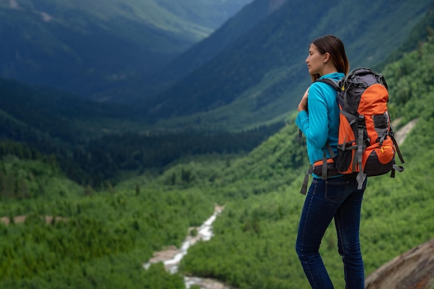 Backpacker bovenop een berg met uitzicht op de vallei