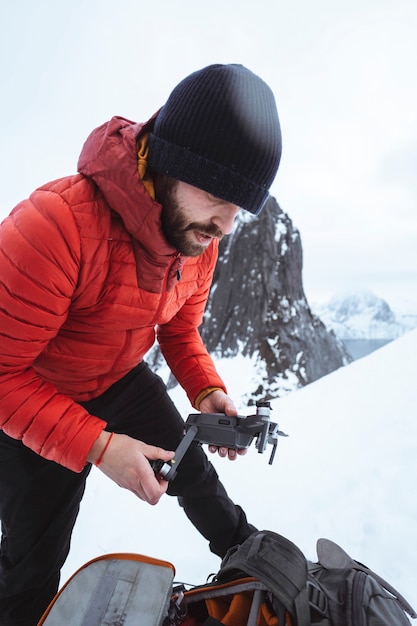 Backpacker die een drone opzet in de besneeuwde Segla-berg, Noorwegen