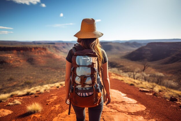 Photo backpacker girl hiking on red rocks up a steep mountain in karijini national park in australia