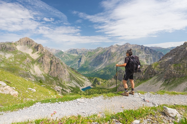 Backpacker hiking on footpath and looking at expansive view from the top