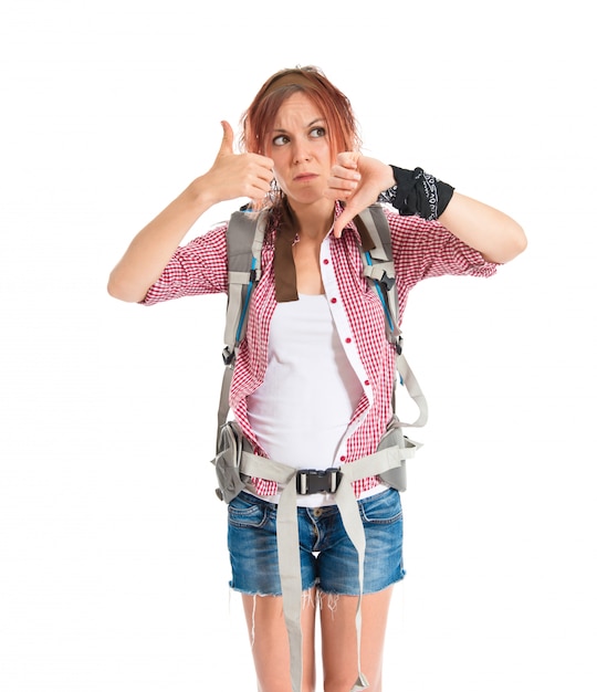 Backpacker making a good-bad sign over white background