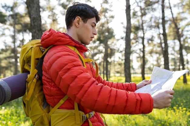 Backpacker man standing in the forest and looking at the map
with nature in the background caucasian man in nature backpacker
traveller