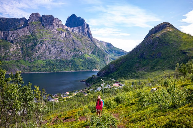 backpacker meisje wandelt hesten trailhead met uitzicht op de stad fjordgard en machtige bergen, senja