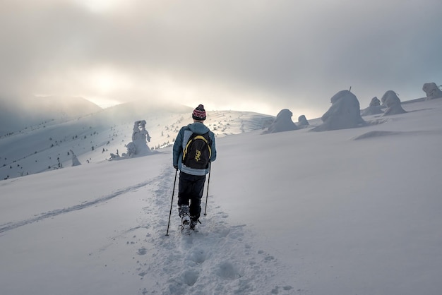 Backpaking tourist hiking in winter mountains