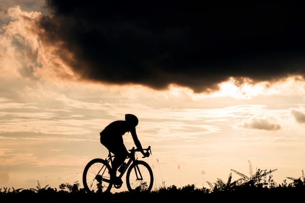 Backside of cyclist ride bicycle at sunset