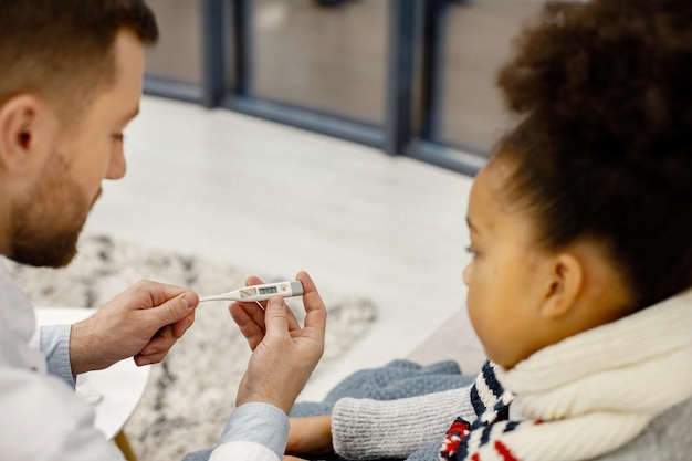 Backside photo of male pediatrician examing sick little black girl