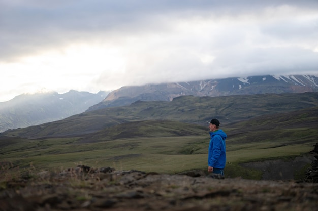 Backside of tall caucasian man wearing jacket standing in over snowy mountain on the Laugavegur track, Iceland. Promoting healthy lifestyle.