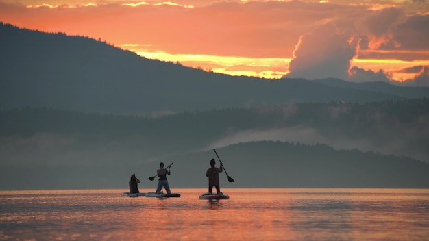 Backside view of rowers paddling at sunset