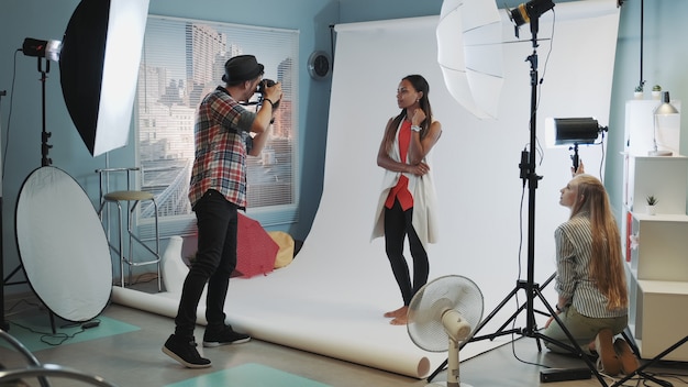 Backstage of the photo session in modern studio: assistant adjusting the spotlight on photo shoot