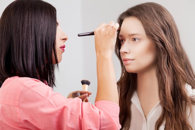 Backstage scene: visagiste at work doing glamour model makeup.