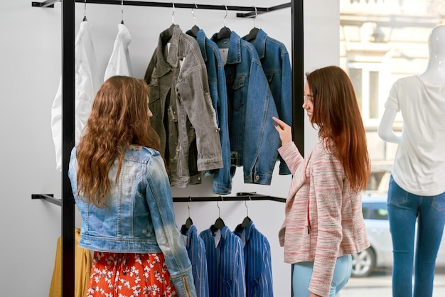 Backview of two girls buying clothes in the shop.