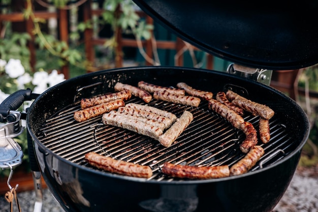 Photo backyard bbq closeup of grilling sausages of meat on barbecue man preparing tasty sausages