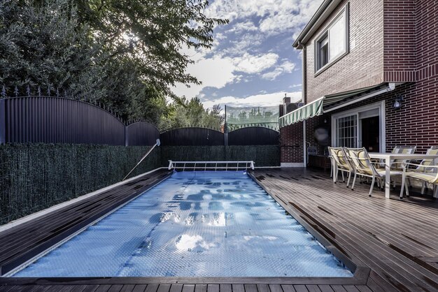 Фото Задний двор одноквартирного дома с бассейном, покрытым выдвижным защитным полотном