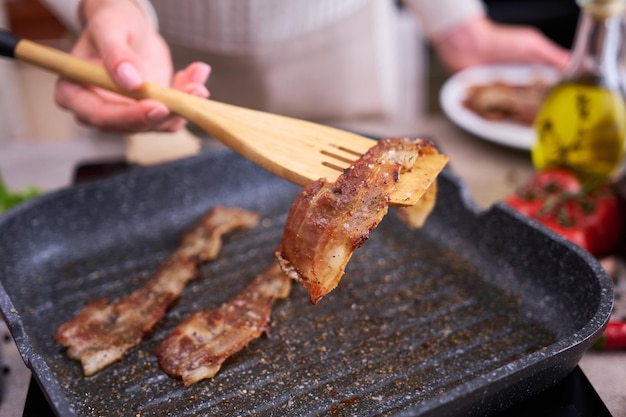 Bacon Being Cooked in grill frying pan Skillet at domestic kitchen