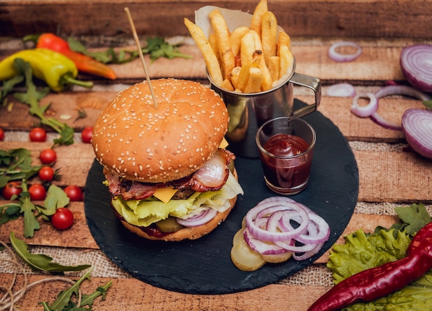 Bacon burger with beef and french fries on wooden table