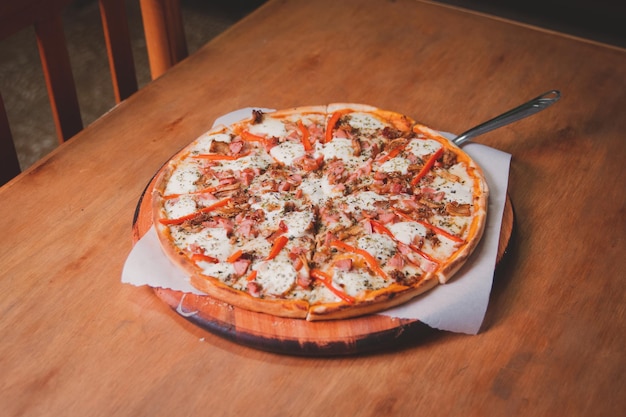 Bacon and ham pizza served on a wooden table