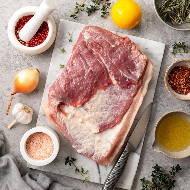 Bacon and ingredients for making homemade porchetta A traditional Italian dish for the holidays on a gray concrete background