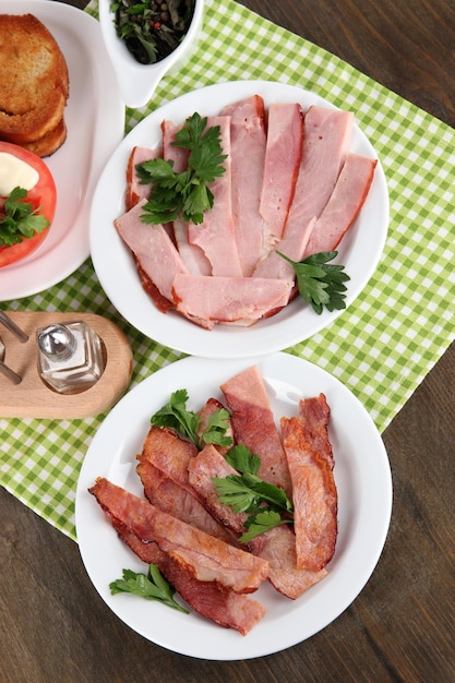 Bacon on plates on napkin on wooden table