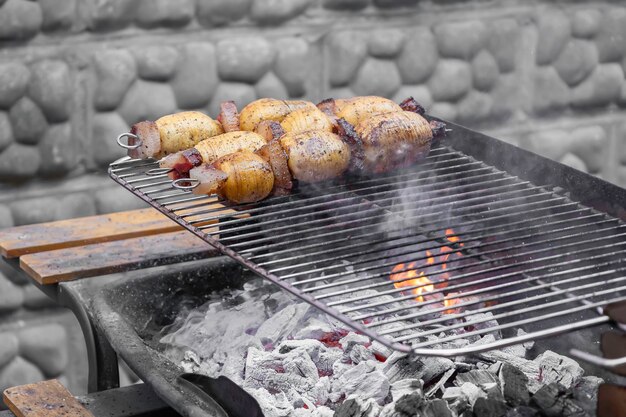 Photo bacon and potatoes grilling over charcoal fire