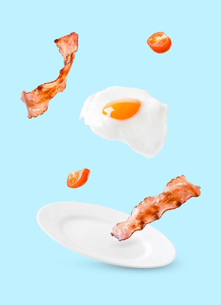 Photo bacon tomatos and egg as english breakfast levitate over a plate on a blue background