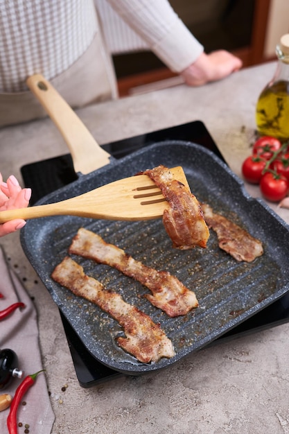 Bacon wordt gekookt in grill koekenpan Koekenpan bij binnenlandse keuken