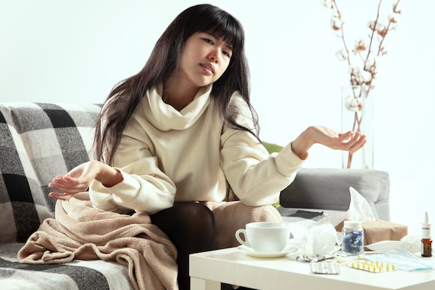 Bacterial Young woman wrapped in a plaid looks sick ill sneezing and coughing sitting