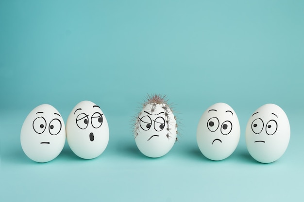 Foto concetto di cattivo personaggio. uovo spinoso. cinque uova bianche con facce disegnate