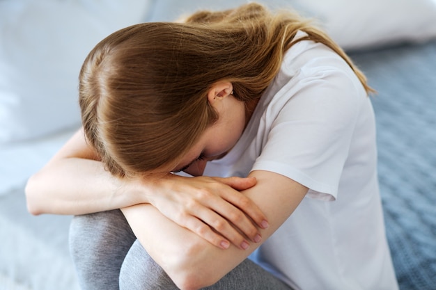 Bad day. Miserable fair-haired woman sitting and crying and having her head down